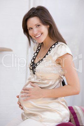 Pregnant woman sitting in living room smiling