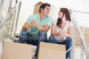 Couple sitting on staircase with boxes in new home smiling