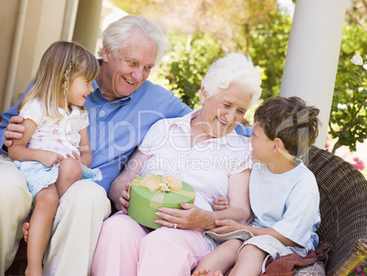 Grandparents with grandchildren on patio with gift smiling