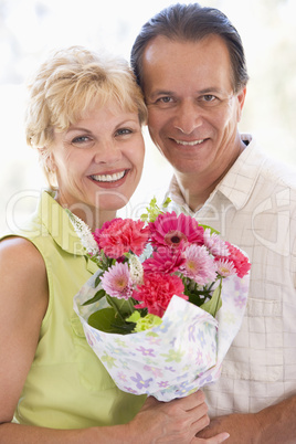 Husband and wife holding flowers and smiling