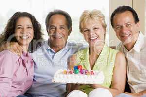 Two couples in living room with cake smiling