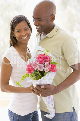 Husband and wife holding flowers and smiling