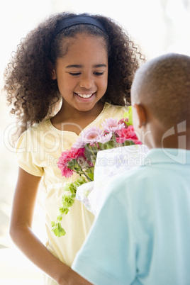 Young boy giving young girl flowers and smiling