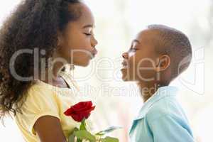 Young boy giving young girl rose and smiling