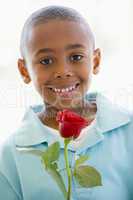 Young boy holding rose smiling