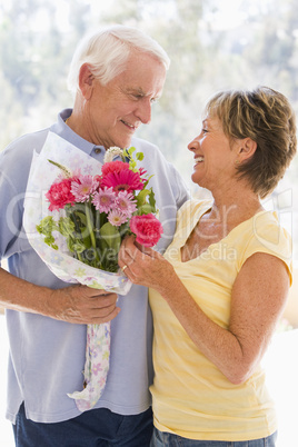 Husband giving wife flowers and smiling