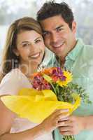 Husband and wife holding flowers and smiling