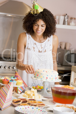 Woman at party fixing cake on table smiling