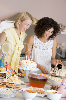 Two women at party getting sandwiches smiling