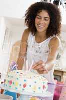 Woman putting candles in cake smiling