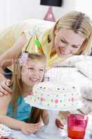 Mother and daughter with birthday cake smiling