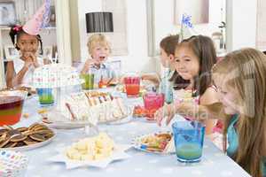 Young children at party sitting at table with food smiling