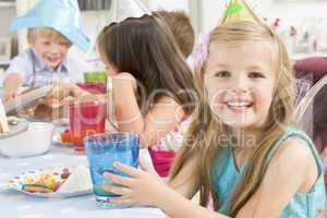 Young girl at party sitting at table with food smiling