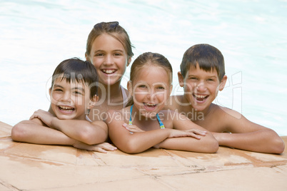 Four young friends in swimming pool smiling