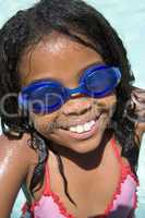 Young girl in swimming pool wearing goggles smiling