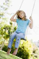 Young girl sitting on swing smiling