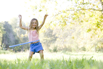 Young girl with hula hoop outdoors smiling