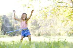 Young girl with hula hoop outdoors smiling