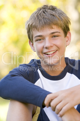 Young boy sitting outdoors smiling