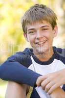 Young boy sitting outdoors smiling