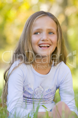 Young girl sitting outdoors smiling