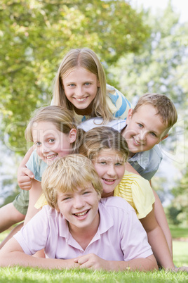 Five young friends piled on each other outdoors smiling
