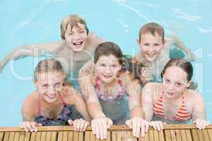 Five young friends in swimming pool smiling