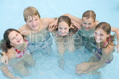 Five young friends in swimming pool smiling