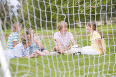 Five young friends on soccer field talking and smiling