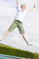 Young boy jumping on trampoline smiling