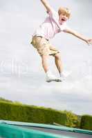 Young boy jumping on trampoline smiling