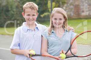 Two young friends with rackets on tennis court smiling
