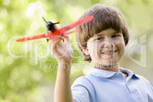 Young boy with toy airplane outdoors smiling