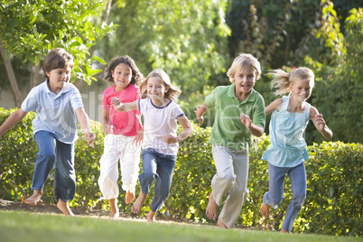 Five young friends running outdoors smiling