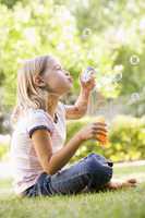 Young girl blowing bubbles outdoors