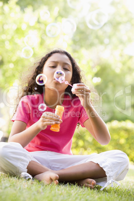 Young girl blowing bubbles outdoors