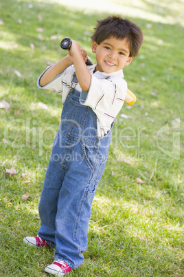 Young boy holding baseball bat outdoors smiling