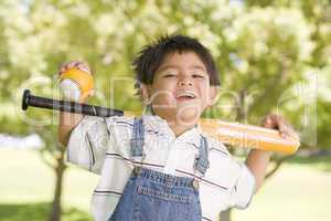 Young boy holding baseball bat outdoors smiling