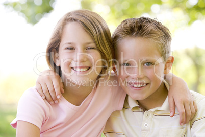 Brother and sister sitting outdoors smiling