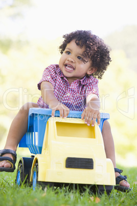 Young boy playing on toy dump truck outdoors