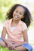 Young girl sitting outdoors smiling