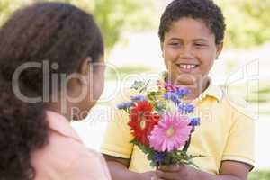 Young boy giving young girl flowers and smiling