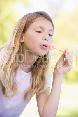 Young girl blowing bubbles outdoors