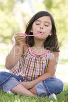 Young girl blowing bubbles outdoors