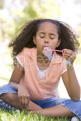 Young girl blowing bubbles outdoors