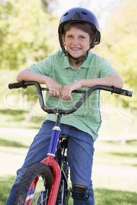 Young boy on bicycle outdoors smiling