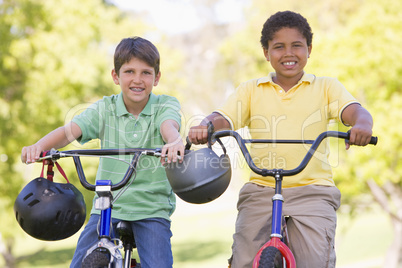 Two young boys on bicycles outdoors smiling