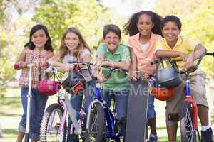 Five young friends with bicycles scooters and skateboard outdoor