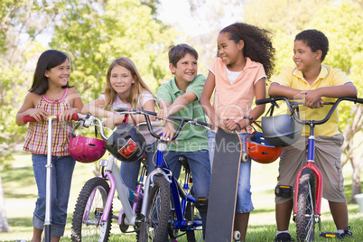 Five young friends with bicycles scooters and skateboard outdoor