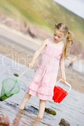 Young girl at beach with net and pail